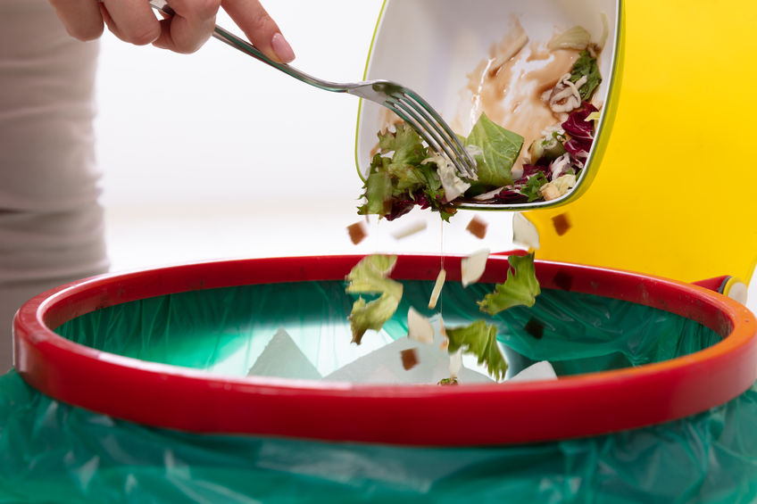 Domestic Food Waste; Woman Throwing Vegetables In Trash Bin